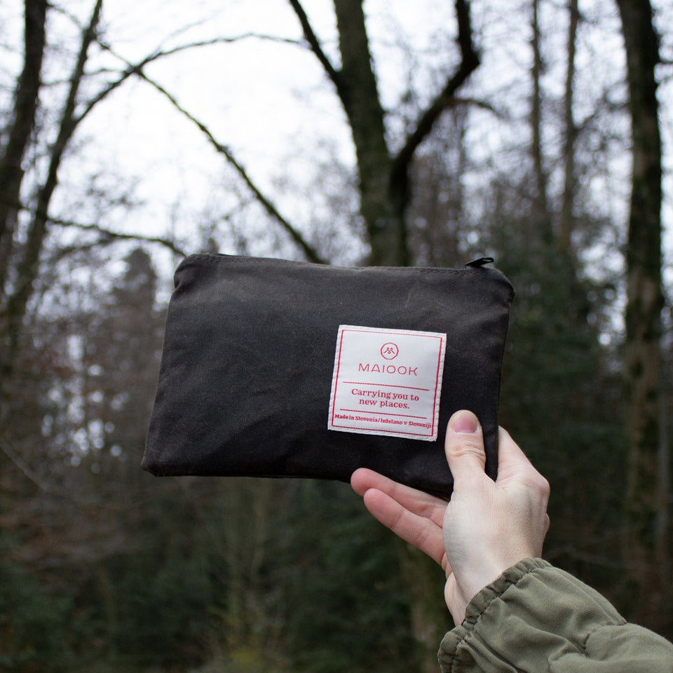 hand holding a wax canvas pouch with woods for a backdrop