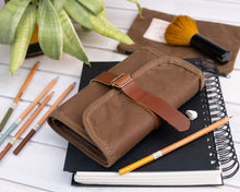 Load image into Gallery viewer, waxed canvas pencil roll on a notebook with pencils next to it