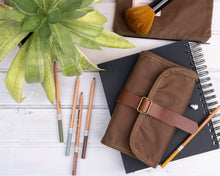 Load image into Gallery viewer, waxed canvas pencil roll from the top on a notebook with pencils next to it