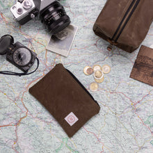 Load image into Gallery viewer, brown waxed canvas pouch on a table with a map, Dopp kit, camera, compass and some coins