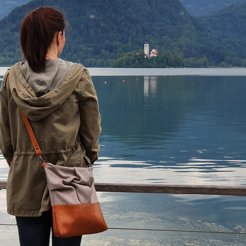a woman in a green parka and a brown handbag overlooking lake Bled