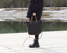 Load image into Gallery viewer, wonam in black holding olive green waxed canvas crossbody bag in hand
